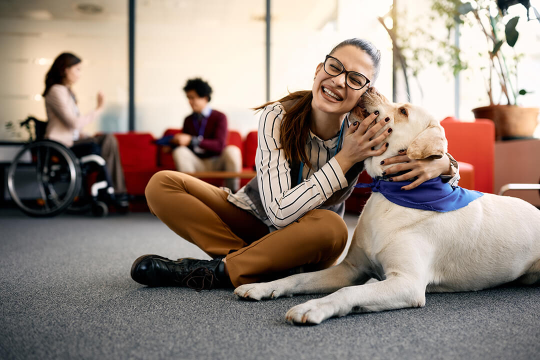 Woman sitting on the floor hugging a therapy dog.